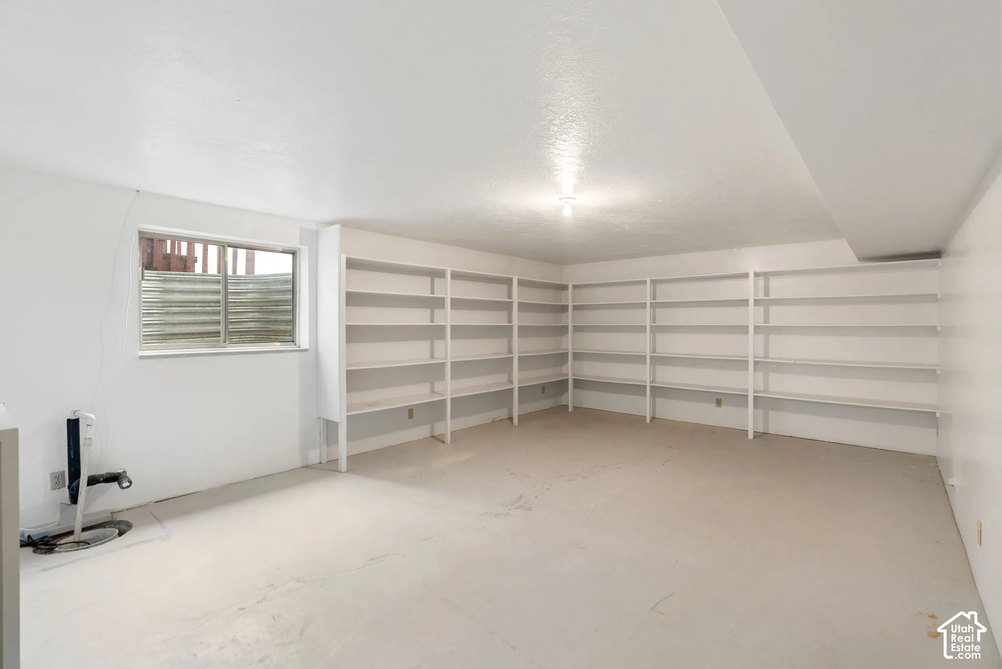 Extensive built-in shelving, painted concrete flooring, and a single-pane window