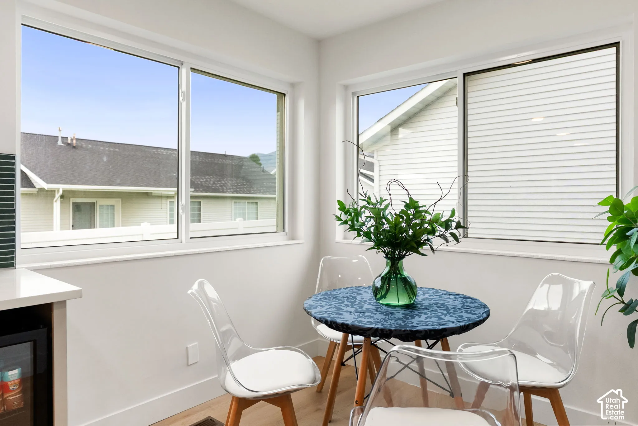 Hardwood-style flooring, white walls, multiple windows with white frames, and a built-in beverage cooler