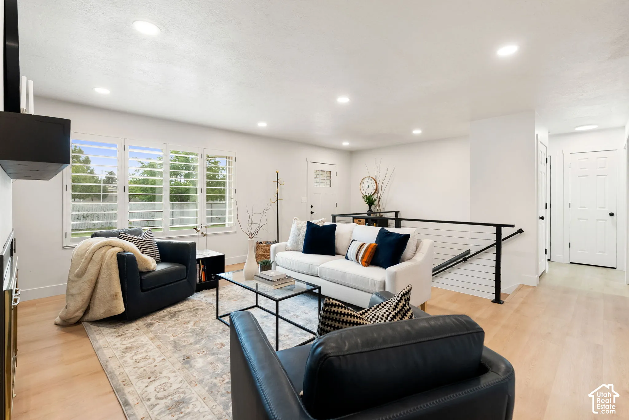 Spacious living area featuring light wood-finish flooring, recessed lighting, and white walls