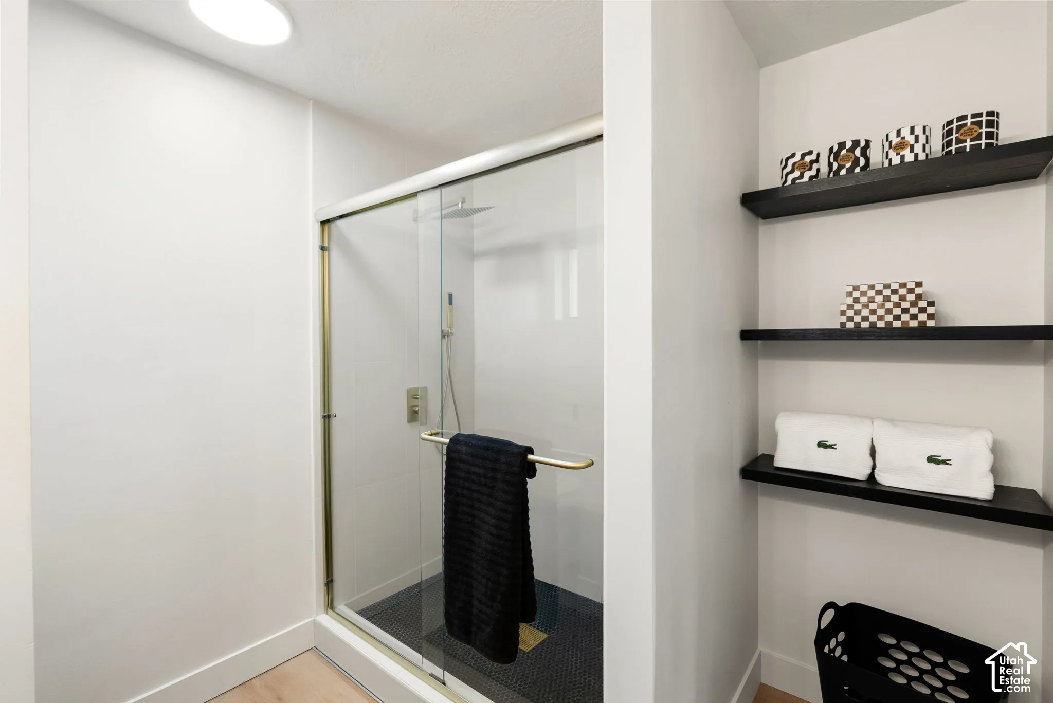 Glass-enclosed shower with gold-tone hardware, rainfall shower head, and mosaic tile flooring