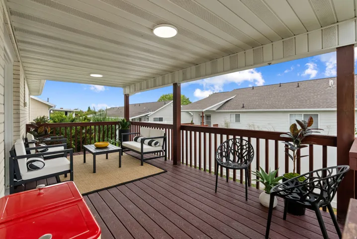Covered outdoor patio with a composite deck, dark wood-tone railing, and recessed lighting