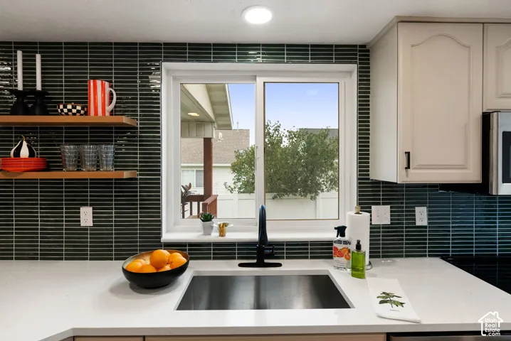 White countertop with an undermount sink, a matte black faucet, and a subway tile backsplash