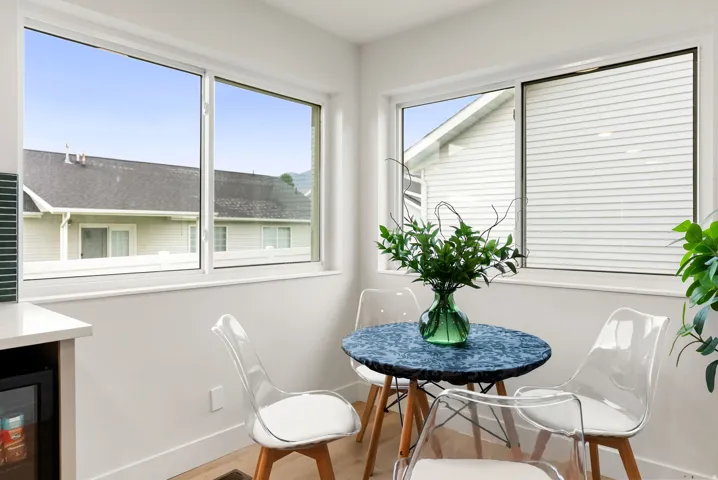 Hardwood-style flooring, white walls, multiple windows with white frames, and a built-in beverage cooler