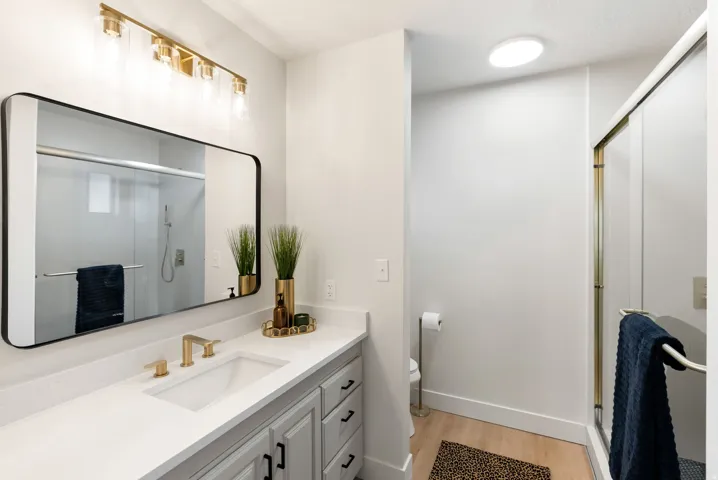 Vanity with integrated sink, gold-finish faucet, and modern black-framed mirror