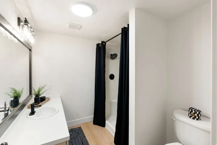 Bathroom with a single vanity, undermount sink, black faucet, and a large mirror