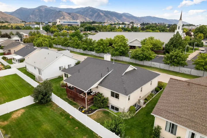 Expansive backyard featuring a white privacy fence, manicured lawn, and raised wood-finish deck