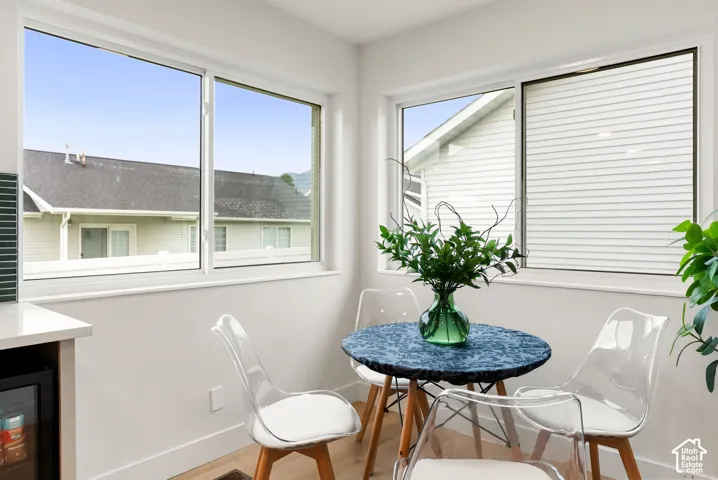 Hardwood-style flooring, white walls, multiple windows with white frames, and a built-in beverage cooler