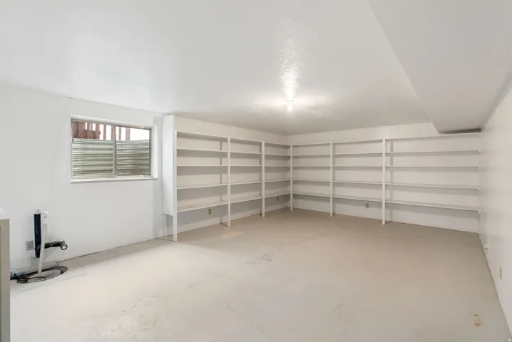 Extensive built-in shelving, painted concrete flooring, and a single-pane window