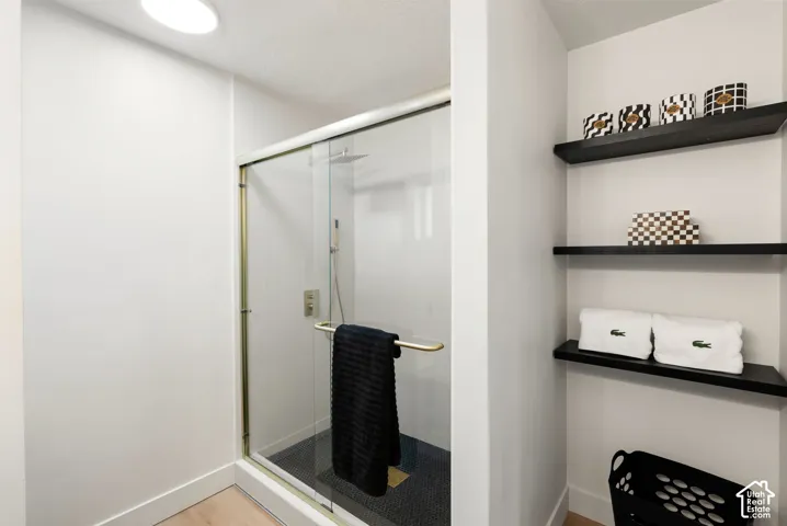 Glass-enclosed shower with gold-tone hardware, rainfall shower head, and mosaic tile flooring