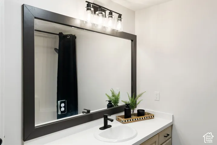 White countertop vanity with an undermount sink, a matte black faucet, and a large framed mirror
