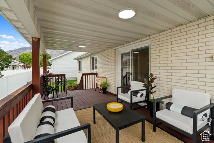 Covered outdoor deck with light brick exterior, sliding glass door access, and mountain backdrop