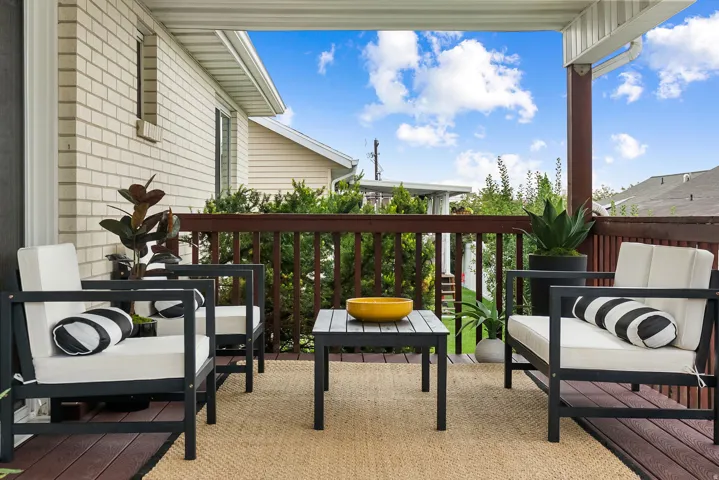 Covered outdoor deck with a dark wood-finish floor and a light-colored woven rug