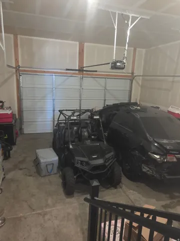 Two-car garage featuring a concrete floor, automatic garage door opener, and unfinished drywall walls