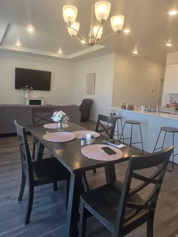 Recessed lighting, tray ceiling, wood-finish flooring, island with bar seating, and a dining area