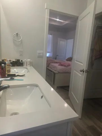 Dual undermount sinks set in a white countertop, modern door hardware, and wood-finish flooring