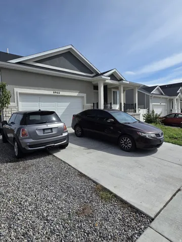 Stucco exterior with a peaked gable roofline, attached two-car garage, and a covered entry