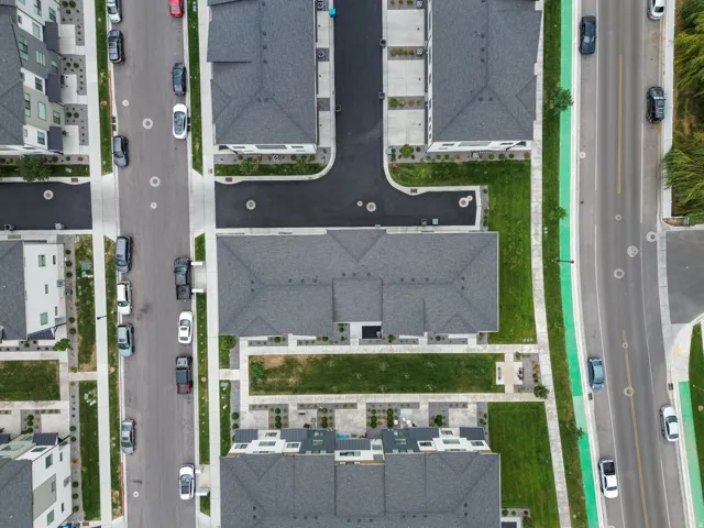 Community with multi-story residences, paved roadways, and green spaces
