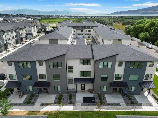 Modern multi-level townhome featuring a dark gray roof, two-tone exterior siding, and covered entryways
