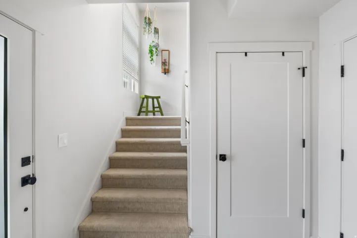 Bright staircase with wood-finish treads and white painted walls, featuring recessed lighting and clean architectural lines