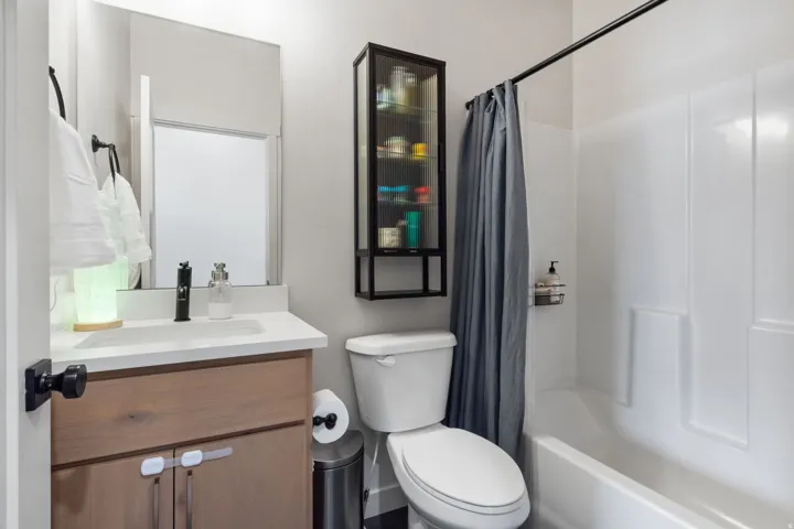 Modern bathroom featuring a wood-finish vanity with dual drawers, white quartz countertop, and matte black hardware