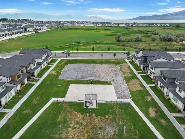 Expansive green space featuring a concrete basketball court, surrounding gravel area, and paved walkways