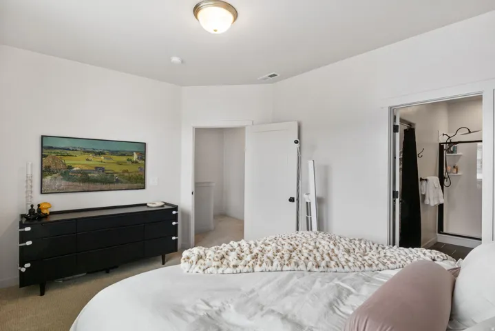 Spacious primary bedroom featuring neutral wall finishes, recessed ceiling lighting, and direct access to an ensuite bathroom with glass-enclosed shower