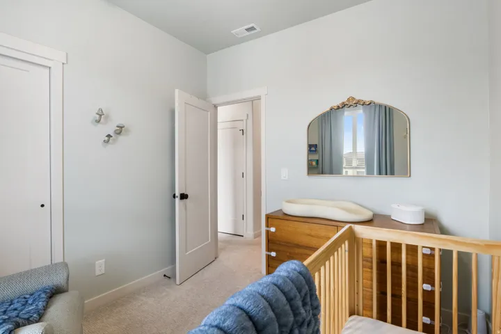 Carpeted flooring, a solid-core door with black hardware, and a window with custom drapery