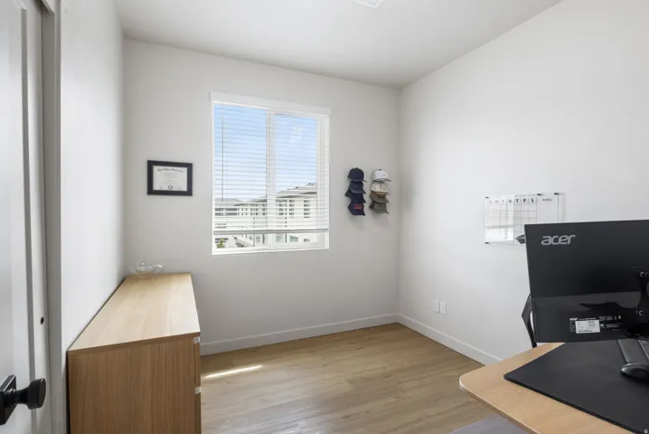Bright room with wood-finish flooring, a white trim window, and white walls