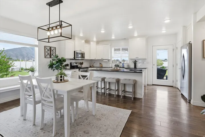 Kitchen with white cabinetry, stainless steel appliances, dark countertops, and wood-finish flooring