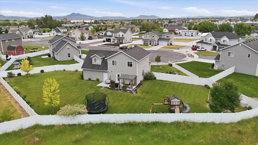 Expansive backyard featuring a manicured lawn, established trees, and white privacy fencing