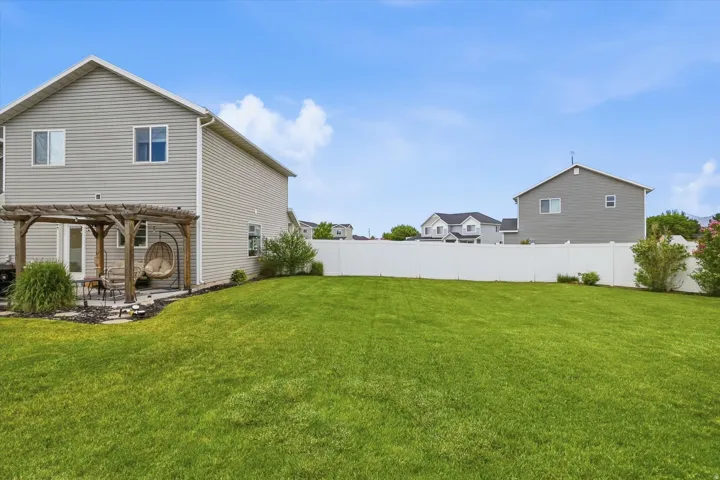Expansive green lawn with a white privacy fence
