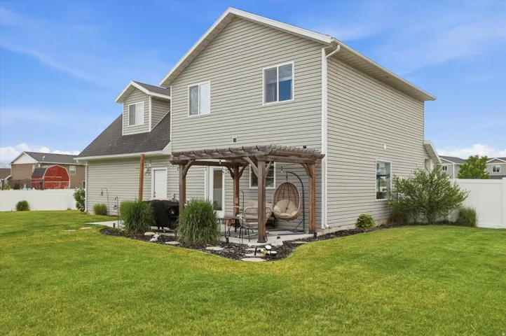 Expansive lawn area with a stone patio featuring a wooden pergola