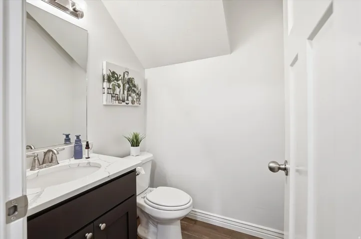 Bathroom featuring a dark wood-finish vanity, white countertop, brushed nickel faucet, and wood-finish flooring