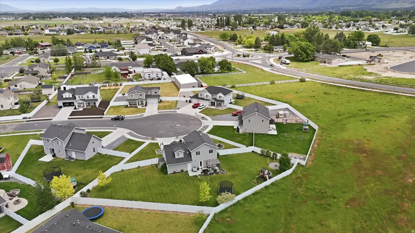 Cul-de-sac community featuring modern homes with dark roofs, green lawns, and perimeter fencing