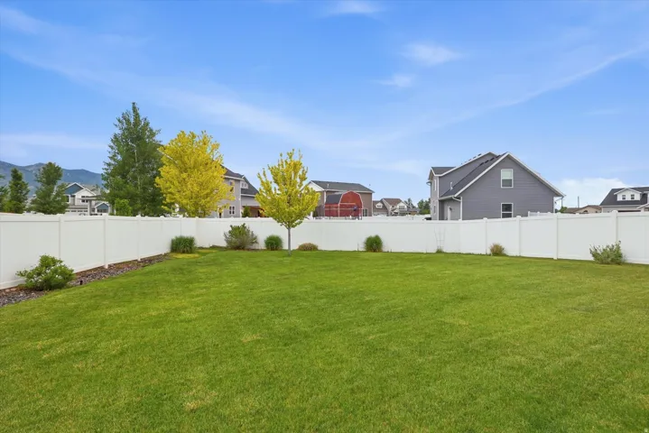 Expansive lawn area with a white privacy fence