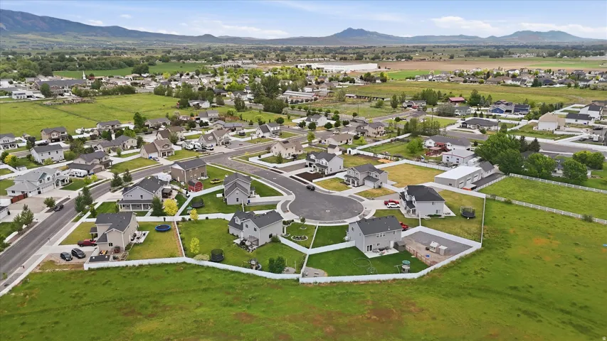Residential community with cul-de-sac streets and individual home lots, bordered by expansive green spaces and distant mountains