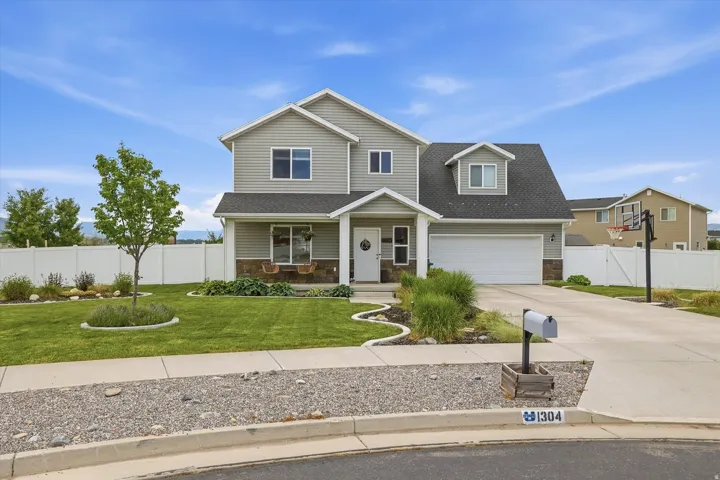 Two-story exterior with light gray siding, stone accents, and a dark shingle roof