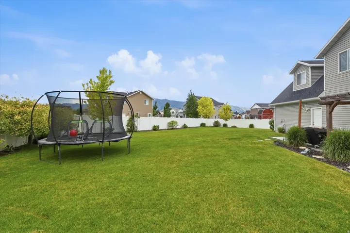 Expansive green lawn, white privacy fencing, and mature landscaping