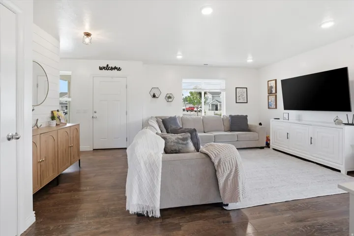 Recessed lighting, wood-finish flooring, white shiplap accent wall, and a front entry door