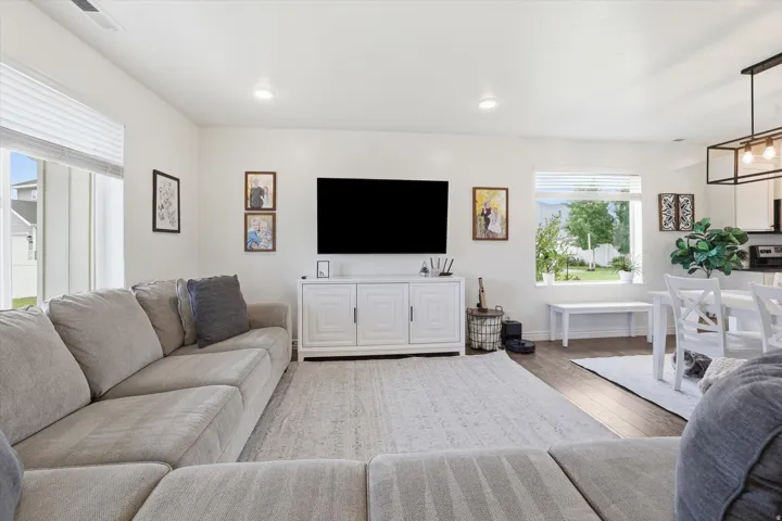 Open-concept living space featuring recessed lighting, wood-finish flooring, and white window blinds