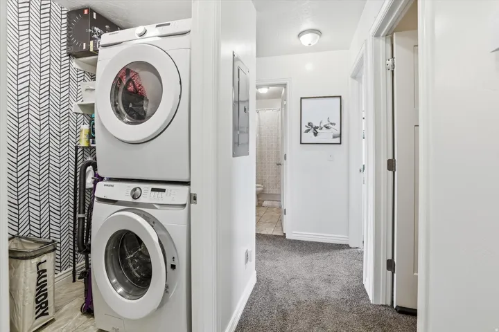 Dedicated laundry area with stacked appliances and patterned wall covering