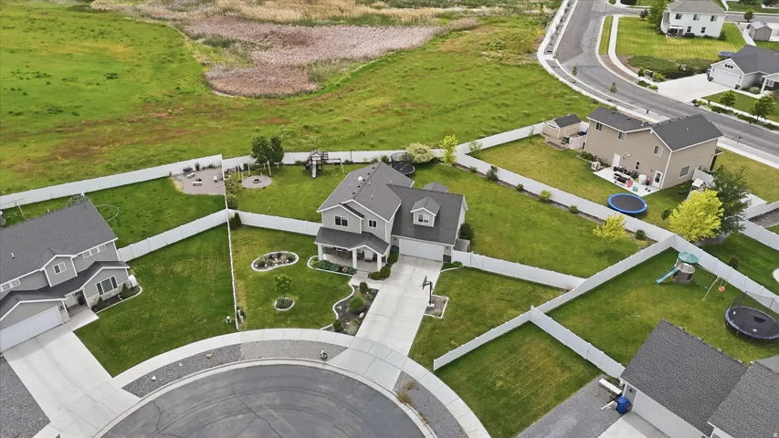 Aerial view of a cul-de-sac with manicured lawns, white fencing, and paved driveways