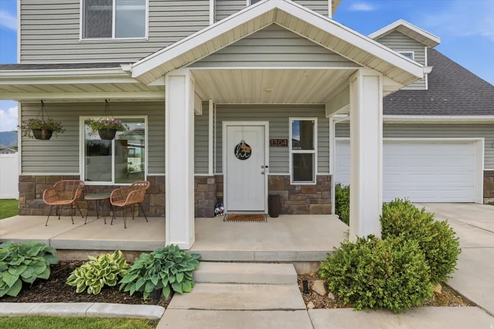 Front exterior featuring a covered porch, stone accent siding, horizontal siding, and an attached garage