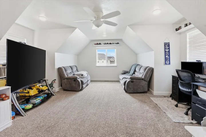 Attic space featuring sloped ceilings, recessed lighting, a ceiling fan, and carpeted flooring