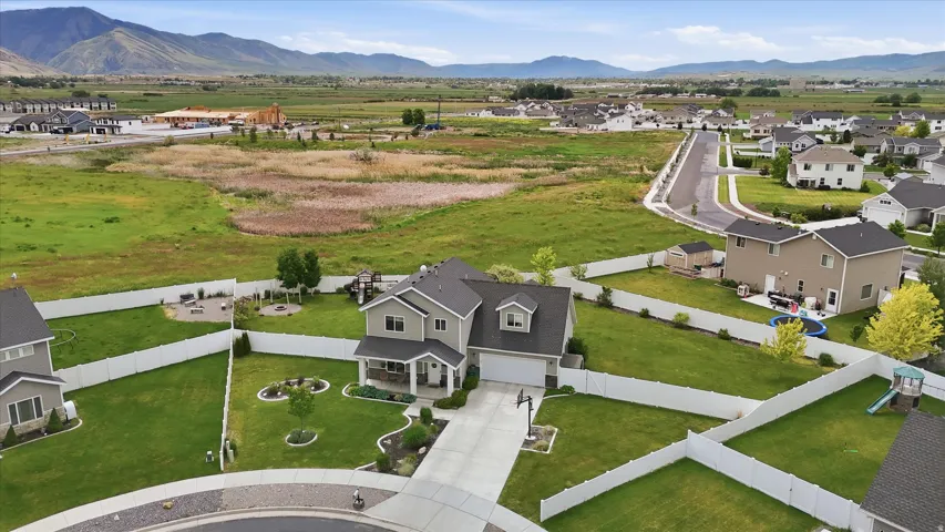 Expansive green lawn, white perimeter fencing, paved driveway, covered front porch, and established landscaping
