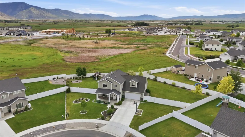 Two-story residence with a covered front porch, an attached garage, and a fenced backyard featuring a manicured lawn