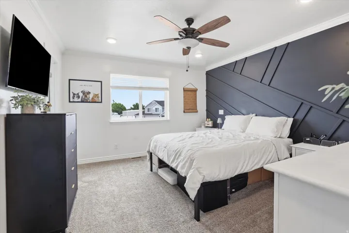 Accent wall with geometric paneling, ceiling fan with wood-finish blades, recessed lighting, and a large window with blinds