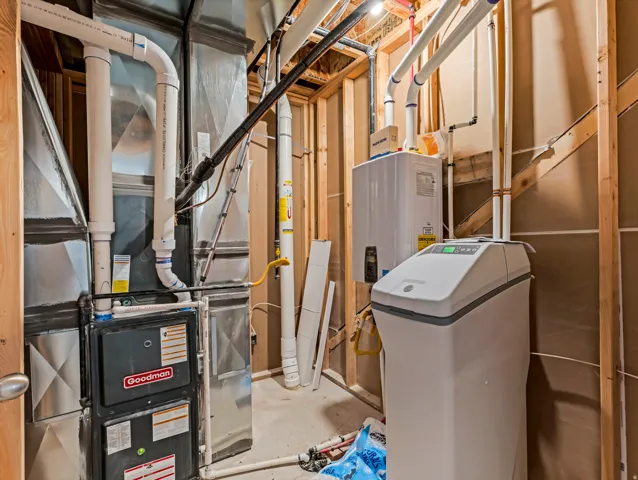 Dedicated utility area featuring a Goodman furnace, a tankless water heater, and a water softening system