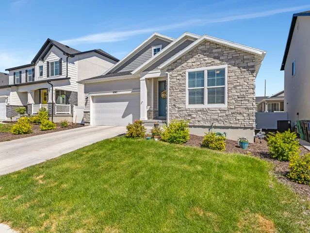 Stone and siding exterior with a covered entry, a single-car garage, established front landscaping, and a manicured lawn