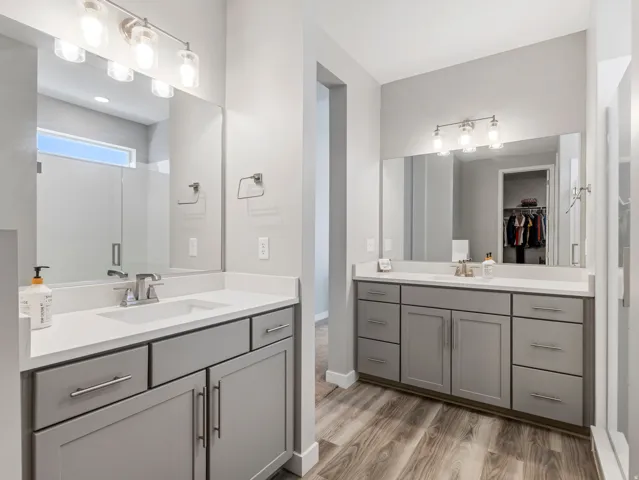 Dual vanities featuring light gray cabinetry, white countertops, and chrome fixtures